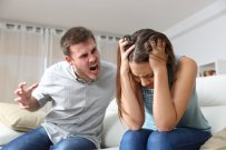 Couple arguing. Husband shouting to a scared wife in a house interior